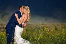 bride and groom embrace in a field of wild flowers